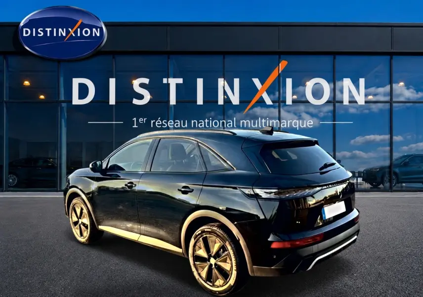 Vue 3/4 arrière droite du SUV DS7 noir brillant avec jantes alliage, garé devant une vitrine Distinxion.