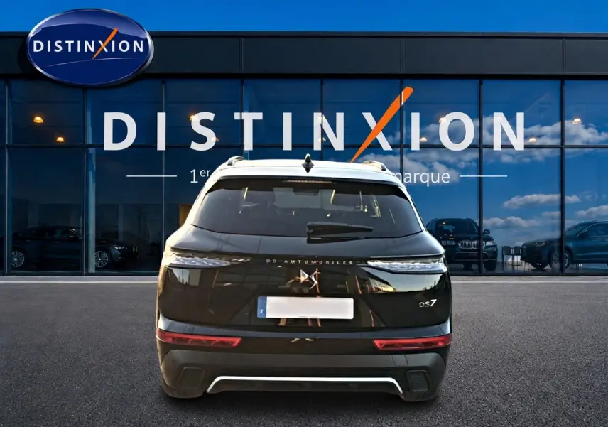 Vue arrière d'un DS7 noir 2026 garé devant une vitrine avec logo Distinxion, feux arrière LED visibles.