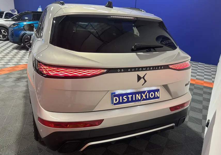 Vue 3/4 arrière droite d’un DS7 Cristal Pearl avec feux arrière LED au design géométrique, dans un showroom.
