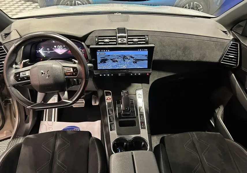 Vue intérieure avant du DS7 BlueHDi 130 avec tableau de bord noir, écran tactile GPS et volant multifonction.