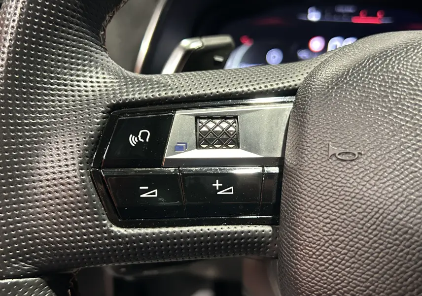 Gros plan sur les commandes de volume et de reconnaissance vocale du volant perforé noir du DS7 2024 Cristal Pearl.