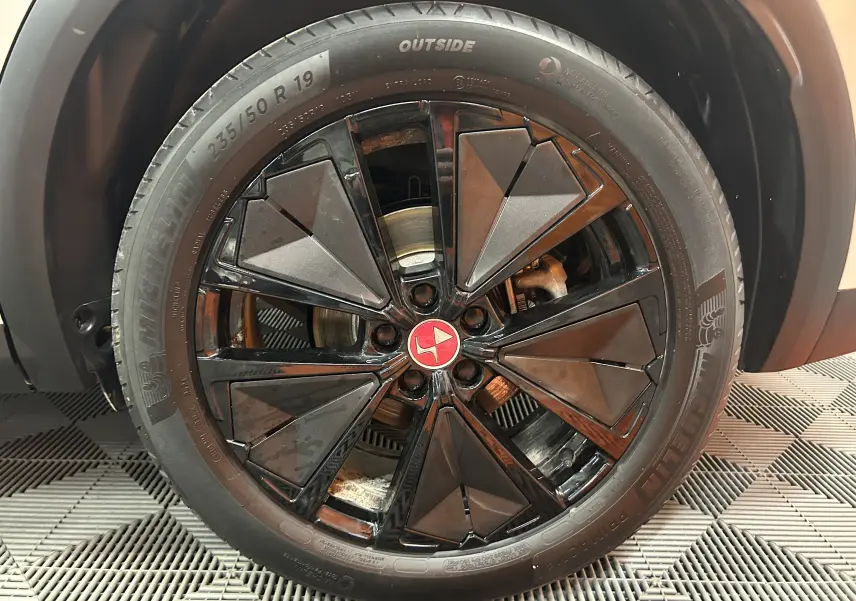Gros plan sur la roue avant droite du DS7 2024 Cristal Pearl, jante noire au design géométrique distinctif.