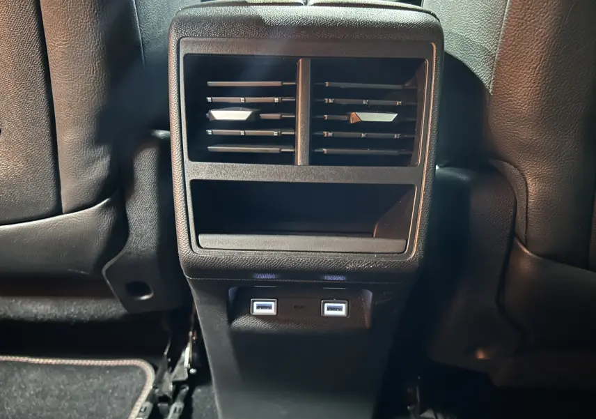 Vue rapprochée de la console arrière noire du DS7 2024 avec bouches d’aération et deux ports USB éclairés.