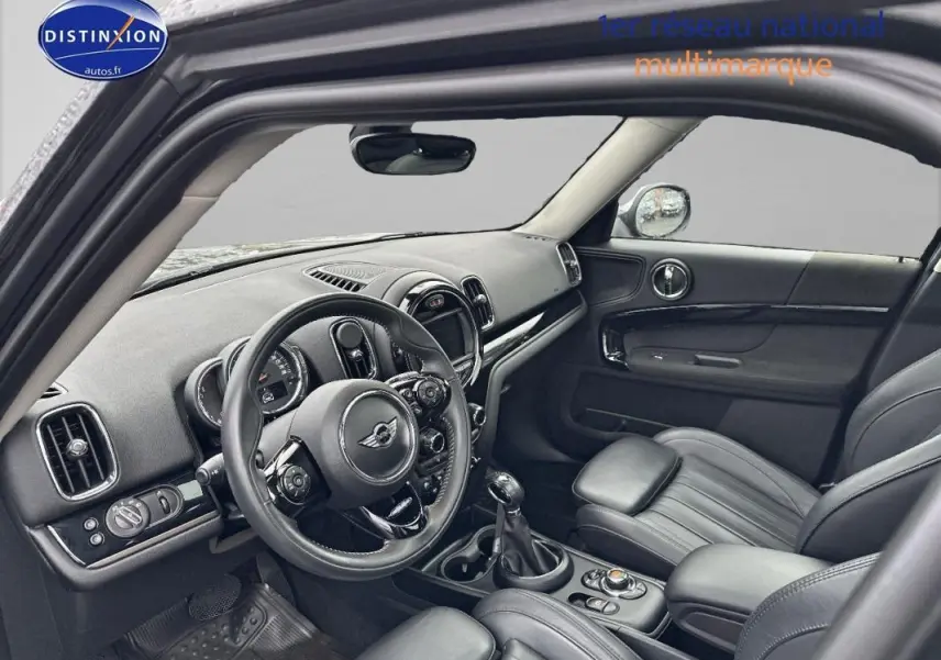 Vue intérieure côté conducteur de la MINI Countryman noire, mettant en valeur le volant sport et la console centrale.
