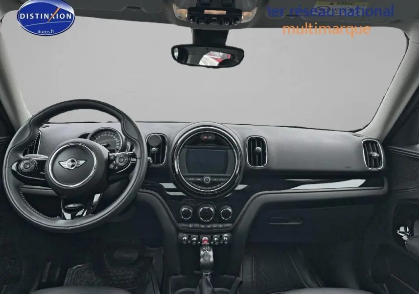 Vue intérieure frontale du tableau de bord noir du MINI Countryman F60 avec volant sport et écran central circulaire.