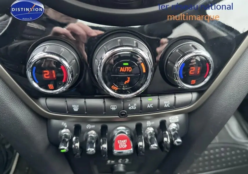 Gros plan sur la console centrale du MINI Countryman noir, montrant les commandes de climatisation automatique et le bouton start/stop rouge.