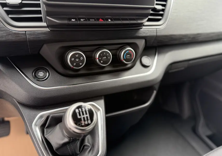 Gros plan sur la console centrale et levier de vitesse manuel du Renault Trafic Combi gris urbain, version 2025.