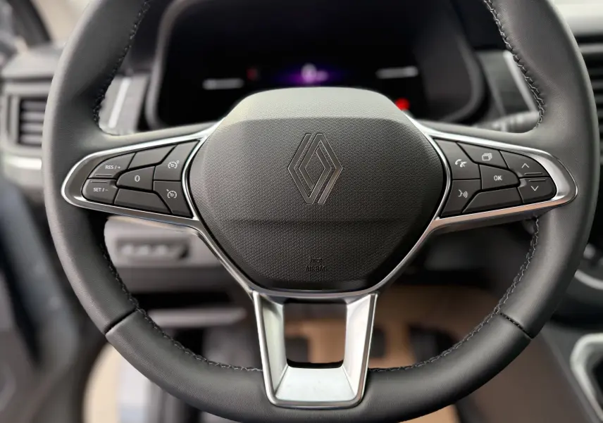 Gros plan sur le volant noir du Renault Trafic Combi 2025 avec commandes intégrées et logo central chromé.