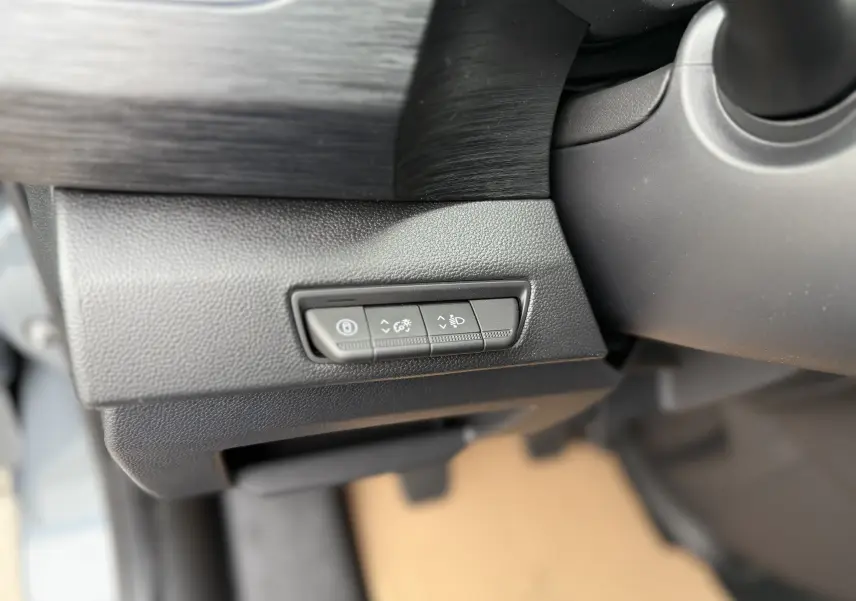 Gros plan sur les commandes de réglage d'éclairage et frein à main électrique dans un Renault Trafic Combi gris urbain 2025.