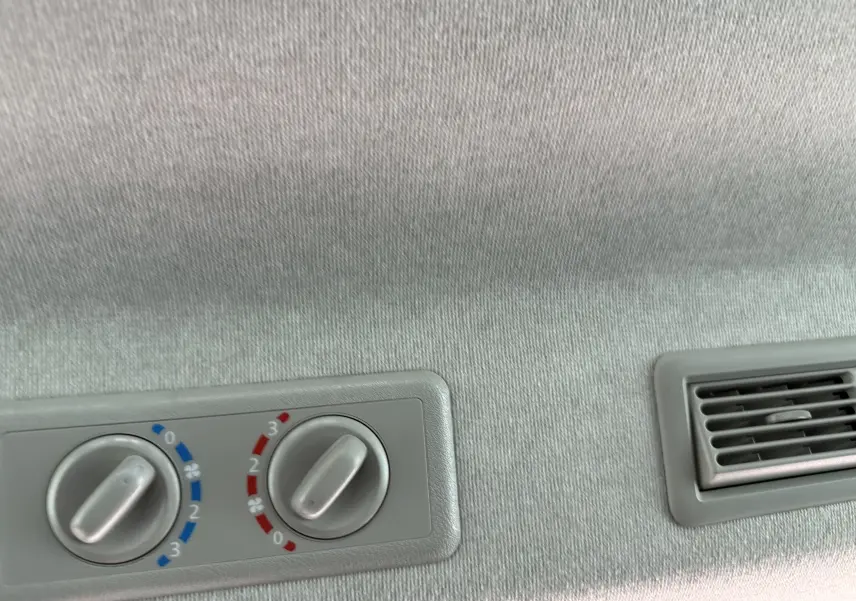 Commandes de climatisation arrière et diffuseur d'air gris clair dans un Renault Trafic Combi gris urbain 3/4 arrière.