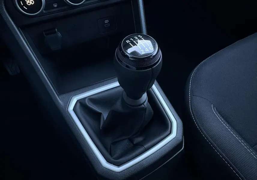 Gros plan sur le levier de vitesses manuel noir du Dacia Jogger 2025, intérieur avec sellerie tissu gris foncé.