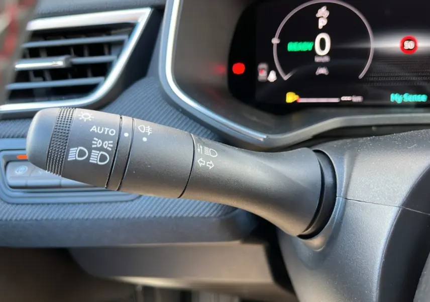 Gros plan sur la commande des feux et clignotants côté gauche du tableau de bord de la Renault Clio gris schiste 2025.