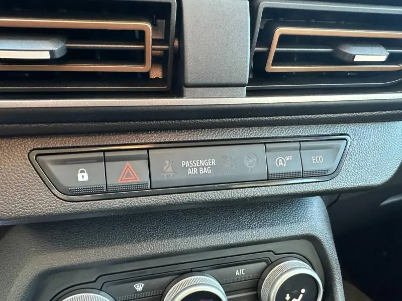 Gros plan sur la console centrale du tableau de bord du Dacia Sandero blanc, montrant les boutons de sécurité et mode ECO.
