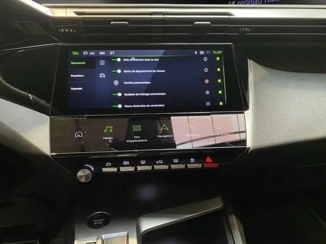 Vue rapprochée du tableau de bord noir de la Peugeot 308 Hybrid 145 e-DCS6 GT 2026 avec écran tactile multifonctions allumé.