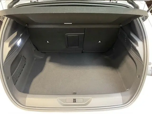 Vue intérieure du coffre ouvert de la Peugeot 308 Hybrid 145 e-DCS6 GT blanc, montrant un espace de rangement propre et spacieux.