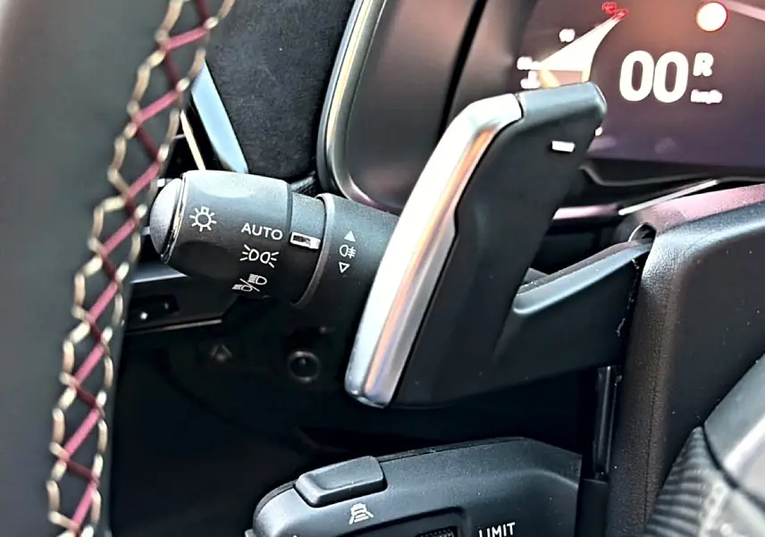 Détail intérieur du levier de vitesses automatique et commandes au volant du DS7 noir, finition Performance Line.