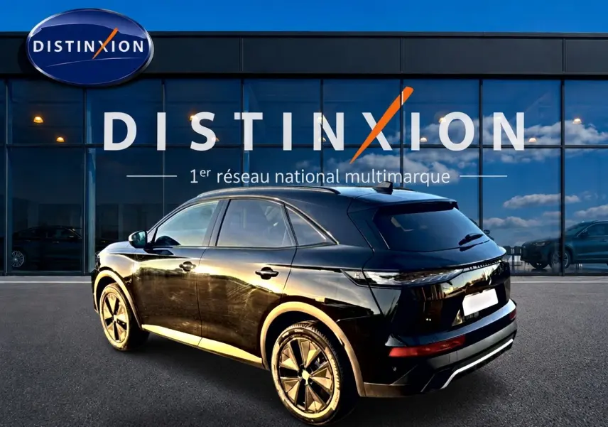 Vue 3/4 arrière droite du SUV DS7 noir brillant, avec jantes alu distinctives, devant une vitrine Distinxion.