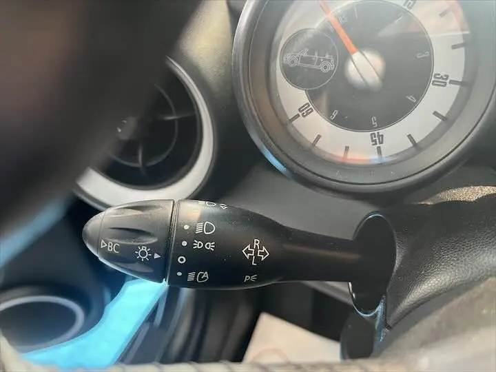 Gros plan sur la commande des clignotants et phares dans l'habitacle d'une MINI Cooper Cabriolet noire de 2012.