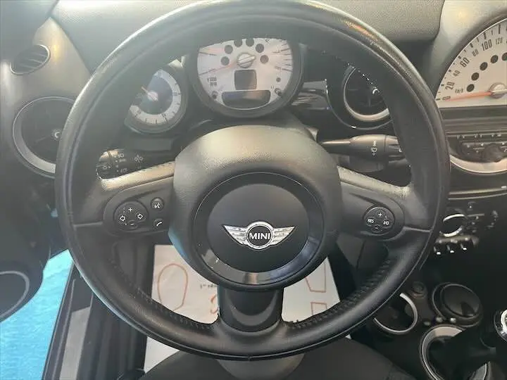 Vue rapprochée du volant noir d'une MINI Cooper Cabriolet 2012, avec tableau de bord et compteurs blancs visibles.