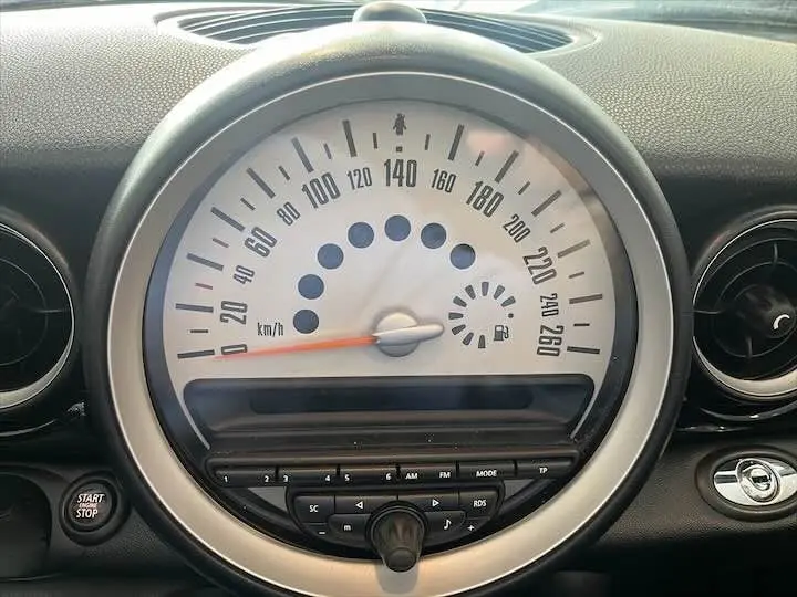 Gros plan sur le compteur de vitesse blanc et la console centrale noire d'une MINI Cooper Cabriolet noire de 2012.