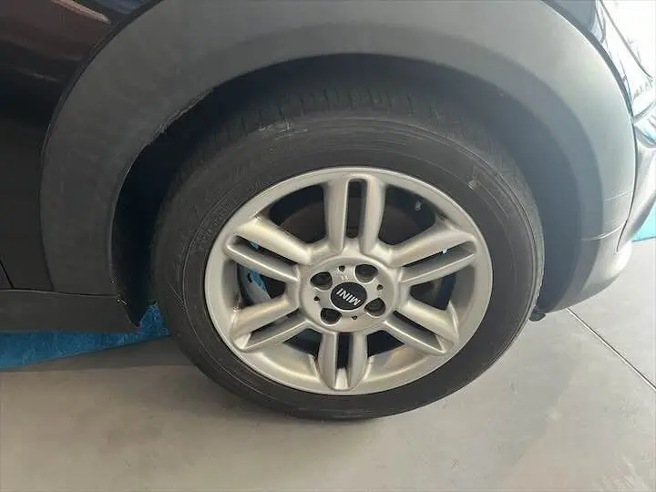 Gros plan sur la roue avant gauche d'une MINI Cooper Cabriolet noire de 2012 avec jante argentée distinctive.