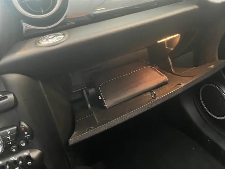 Gros plan sur la boîte à gants ouverte côté passager d'une MINI Cooper Cabriolet noire de 2012.
