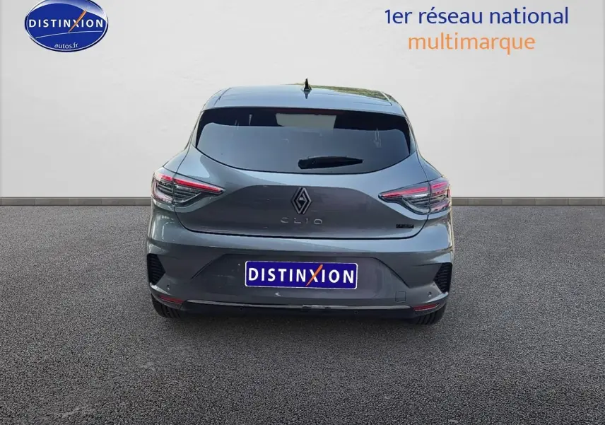 Vue arrière d'une Renault Clio V gris schiste avec feux LED et lunette arrière surteintée sur sol goudronné.
