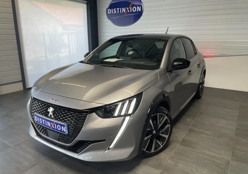 Peugeot 208 gris clair métallisé vue 3/4 avant droit avec toit noir et jantes alliage 17 pouces en intérieur showroom.