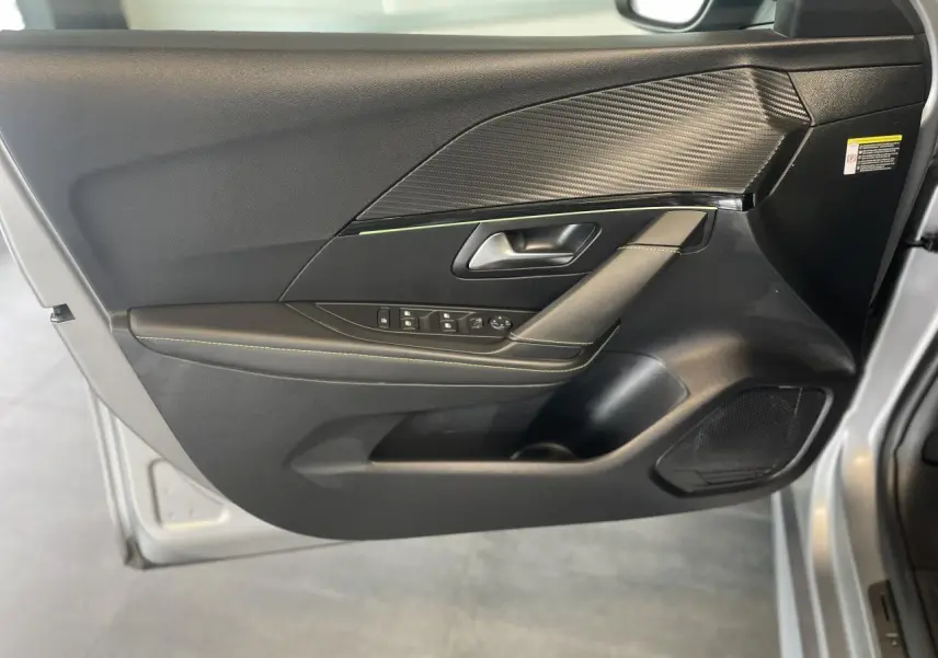 Intérieur côté gauche de la porte PEUGEOT 208 gris clair, avec garniture noire et surpiqûres vertes visibles.