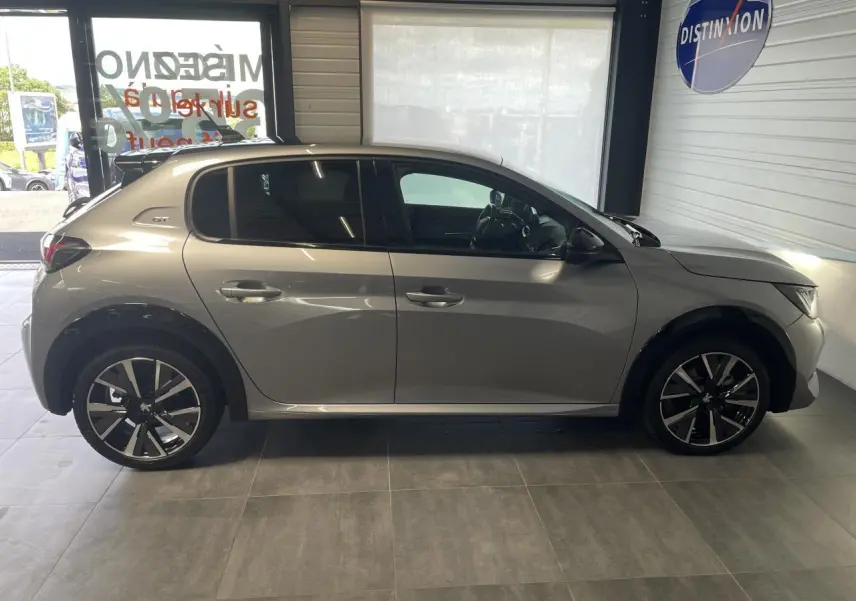 Profil droit d'une Peugeot 208 gris clair Metal Artense avec toit noir et jantes alliage 17'' Bronx en showroom.