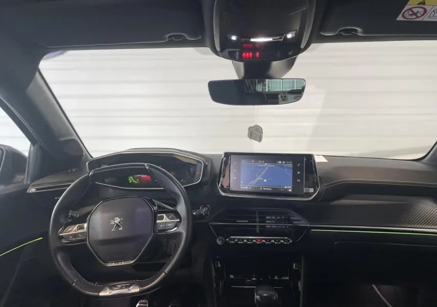 Vue intérieure avant de la Peugeot 208 GT 2023 avec tableau de bord noir, volant compact et écran tactile de navigation.
