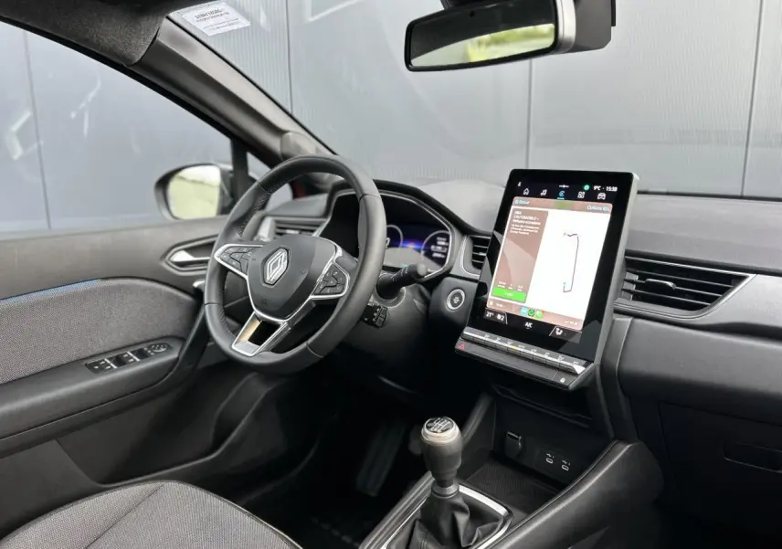 Vue intérieure côté conducteur du Renault Captur 2025, volant, tableau de bord numérique et écran tactile vertical visibles.