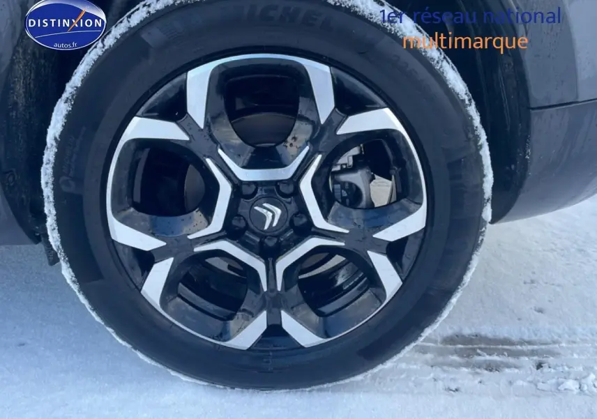 Gros plan sur la jante alu noire et argentée du côté gauche d’un Citroën C5 Aircross gris platinium sur neige.
