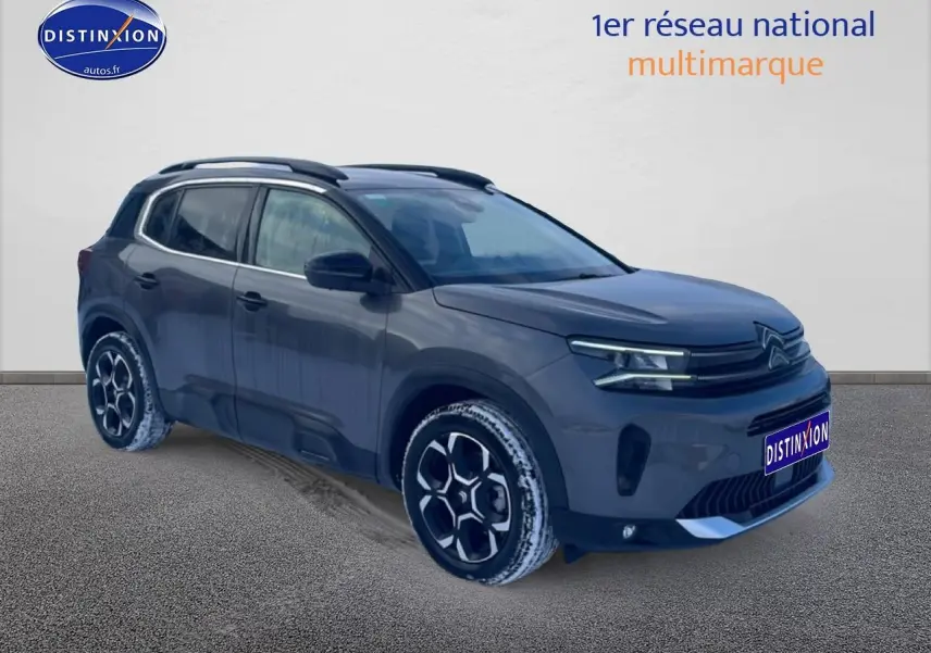 Vue 3/4 avant droit du Citroën C5 Aircross gris platinium avec jantes alu et barres de toit visibles.