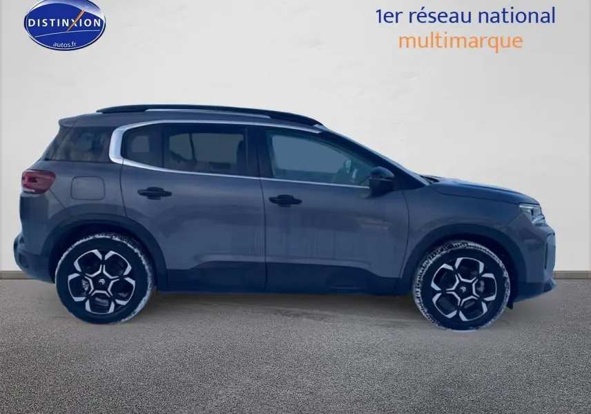 Profil droit du Citroën C5 Aircross gris platinium avec jantes alu et barres de toit visibles sur fond neutre.