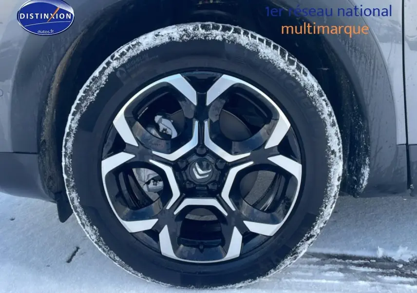 Gros plan sur la roue avant droite du Citroën C5 Aircross gris platinium avec jante alu noire et argent sous la neige.