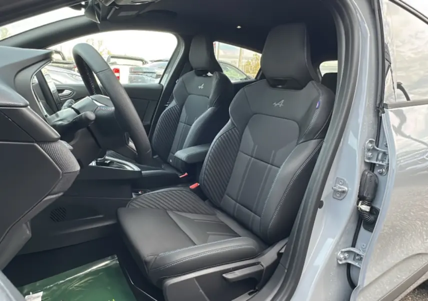 Vue intérieure côté conducteur de la Renault Clio V E-Tech 145 Esprit Alpine Bose avec sièges sport noirs et surpiqûres bleues.