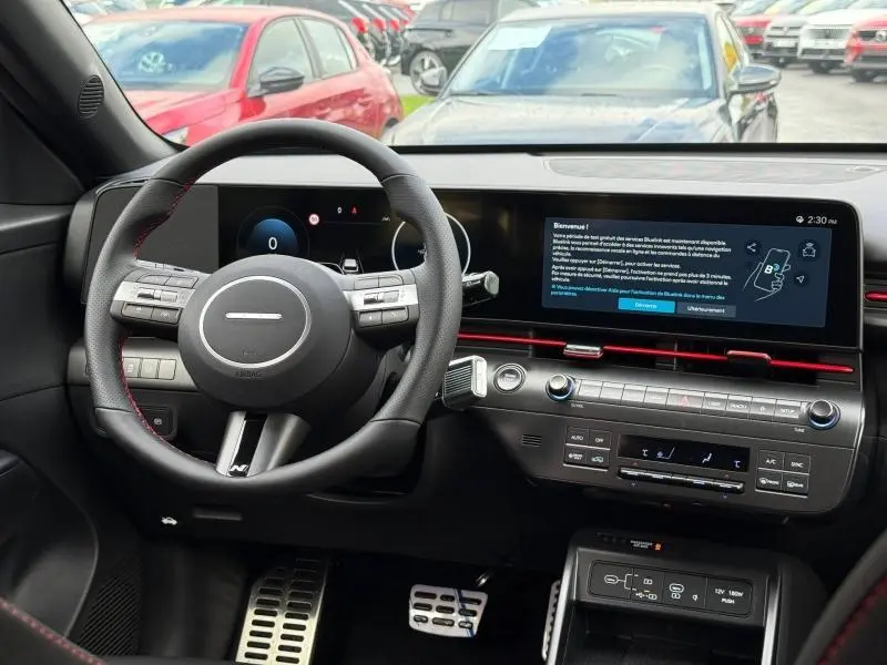 Vue intérieure du poste de conduite du Hyundai KONA 2025, avec volant multifonction et écran tactile large noir.
