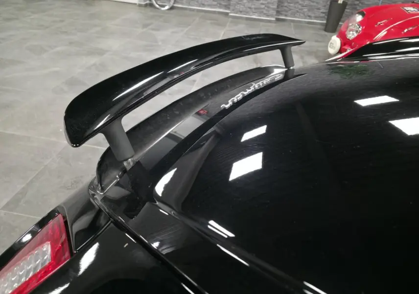 Vue rapprochée de l’aileron arrière noir sur Porsche Cayman 2.7i 2008 avec carrosserie noire brillante.