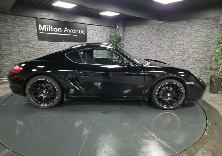 Profil côté gauche de la Porsche Cayman 2.7i noire de 2008 avec jantes SportDesign noires de 19 pouces.