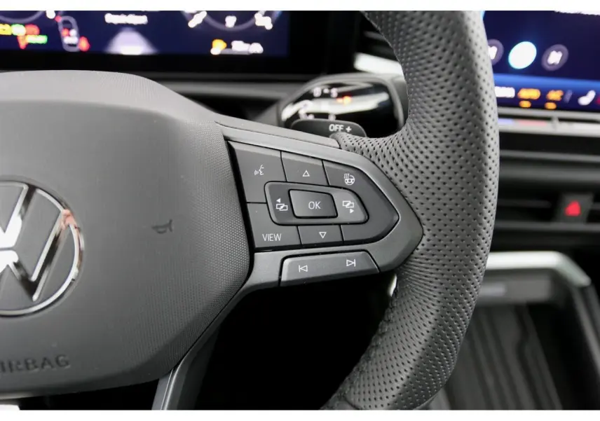 Gros plan sur le volant perforé gris du Volkswagen T-Roc 2026, avec commandes multifonctions visibles à droite.