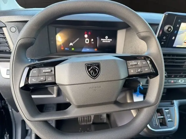 Vue rapprochée du volant multifonctions noir du Peugeot Expert Fourgon 2025 avec tableau de bord numérique et écran tactile.