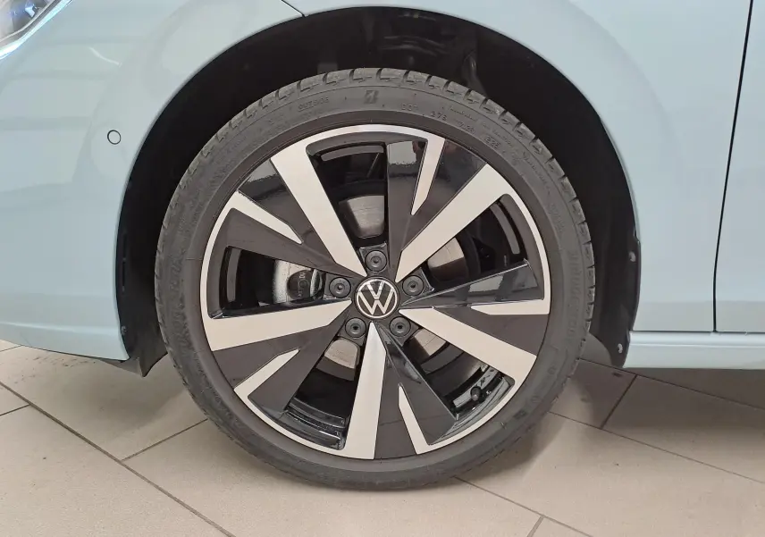 Gros plan sur la jante alliage 18'' Catania bicolore noir et argent d'une Volkswagen Golf Bleu Glacier côté arrière droit.