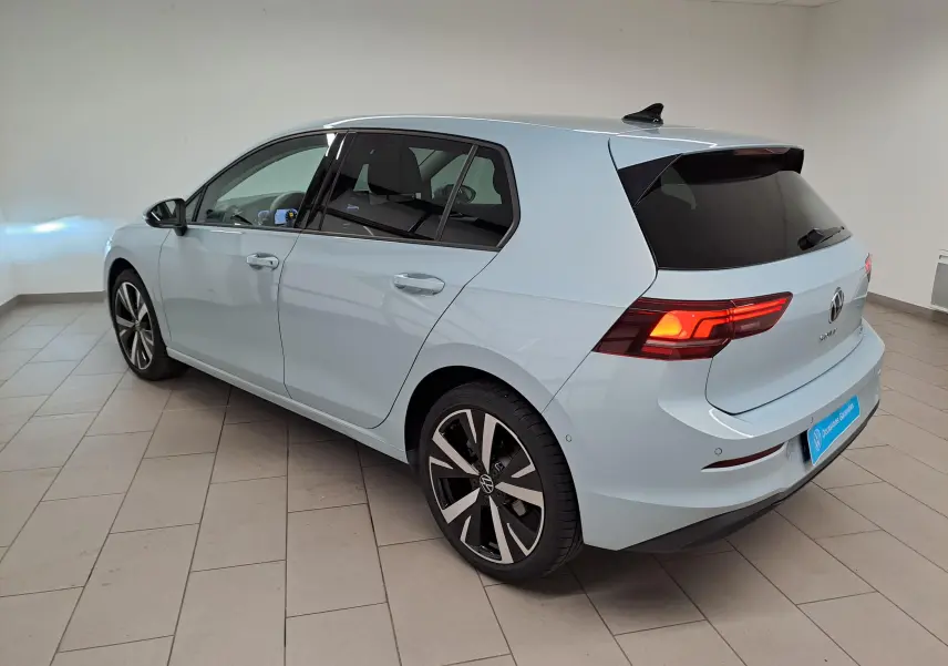 Vue 3/4 arrière droite d'une Volkswagen Golf 1.5 eTSI 2025 en Bleu Glacier avec jantes alliage 18'' Catania.