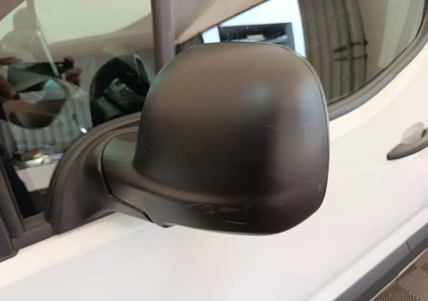 Rétroviseur extérieur noir côté conducteur du Peugeot Partner blanc, vue rapprochée en léger angle avant.