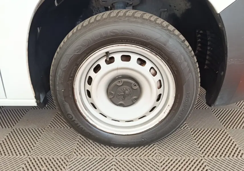 Gros plan sur la roue avant droite blanche du Peugeot Partner 2022, avec jante acier et logo Peugeot central.