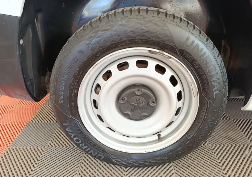 Gros plan sur la roue avant droite blanche du Peugeot Partner 2022 avec jante acier et pneu Uniroyal.