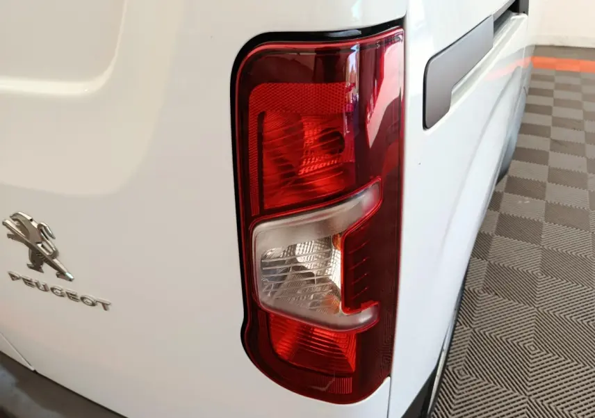 Gros plan sur le feu arrière droit rouge et blanc d’un Peugeot Partner blanc, vue arrière côté droit.
