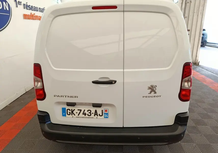 Vue arrière d’un Peugeot Partner blanc 2022 avec portes battantes et feux rouges verticaux, immatriculé en France.
