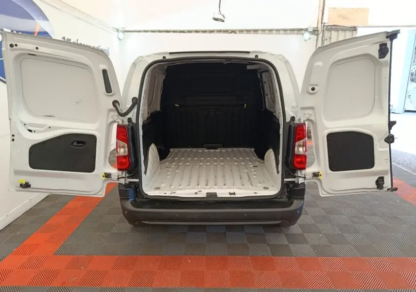 Vue arrière d’un Peugeot Partner blanc 2022 avec portes battantes ouvertes montrant l’espace de chargement vide.